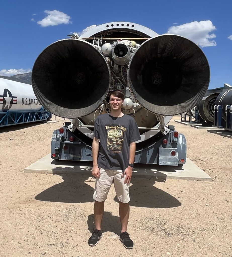 Picture of Seth standing in front of a rocket engine at the museum of nuclear science and history